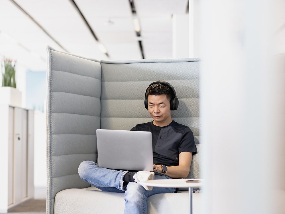 Zaposlenik Henkela sa slušalicama radi koncentrisan na svom laptopu.