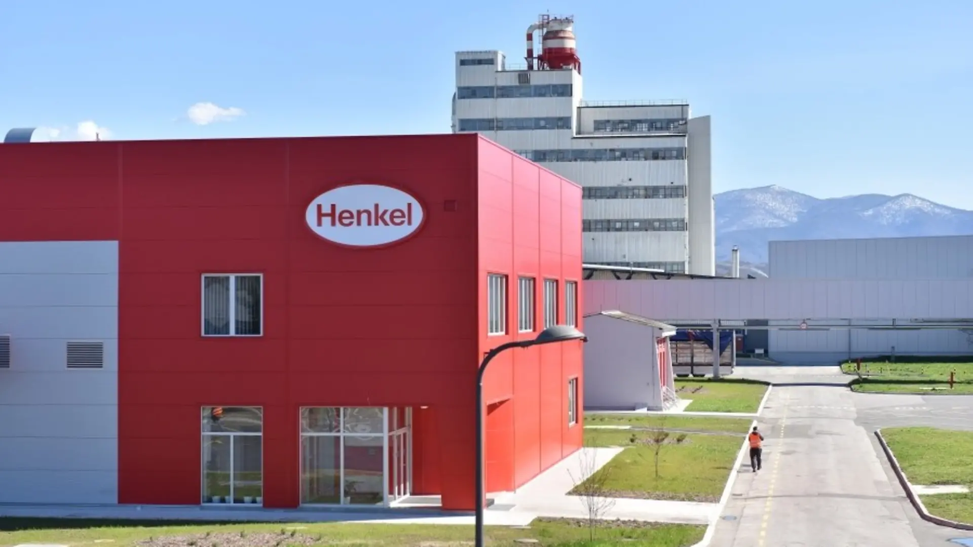 Na fotografiji je crveno-bela zgrada sa Henkel logotipom u prvom planu.